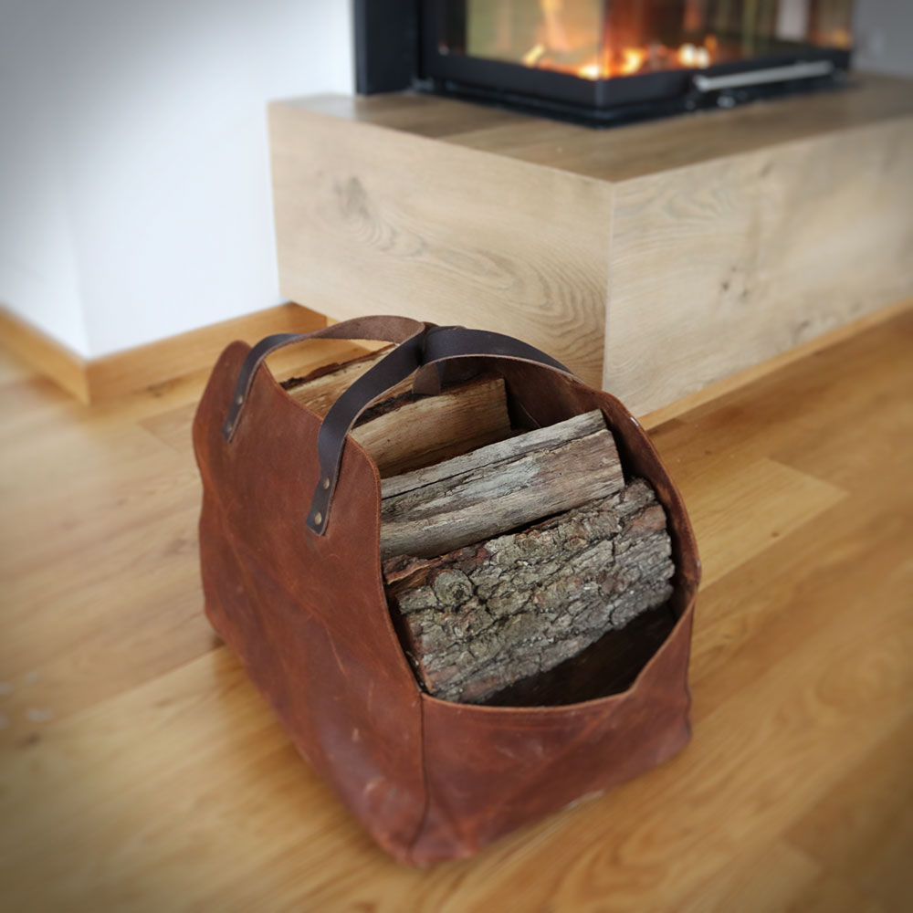 Mit Brennholz gefüllte Kaminholztasche aus Leder Mit Brennholz gefüllte Kaminholztasche aus Leder