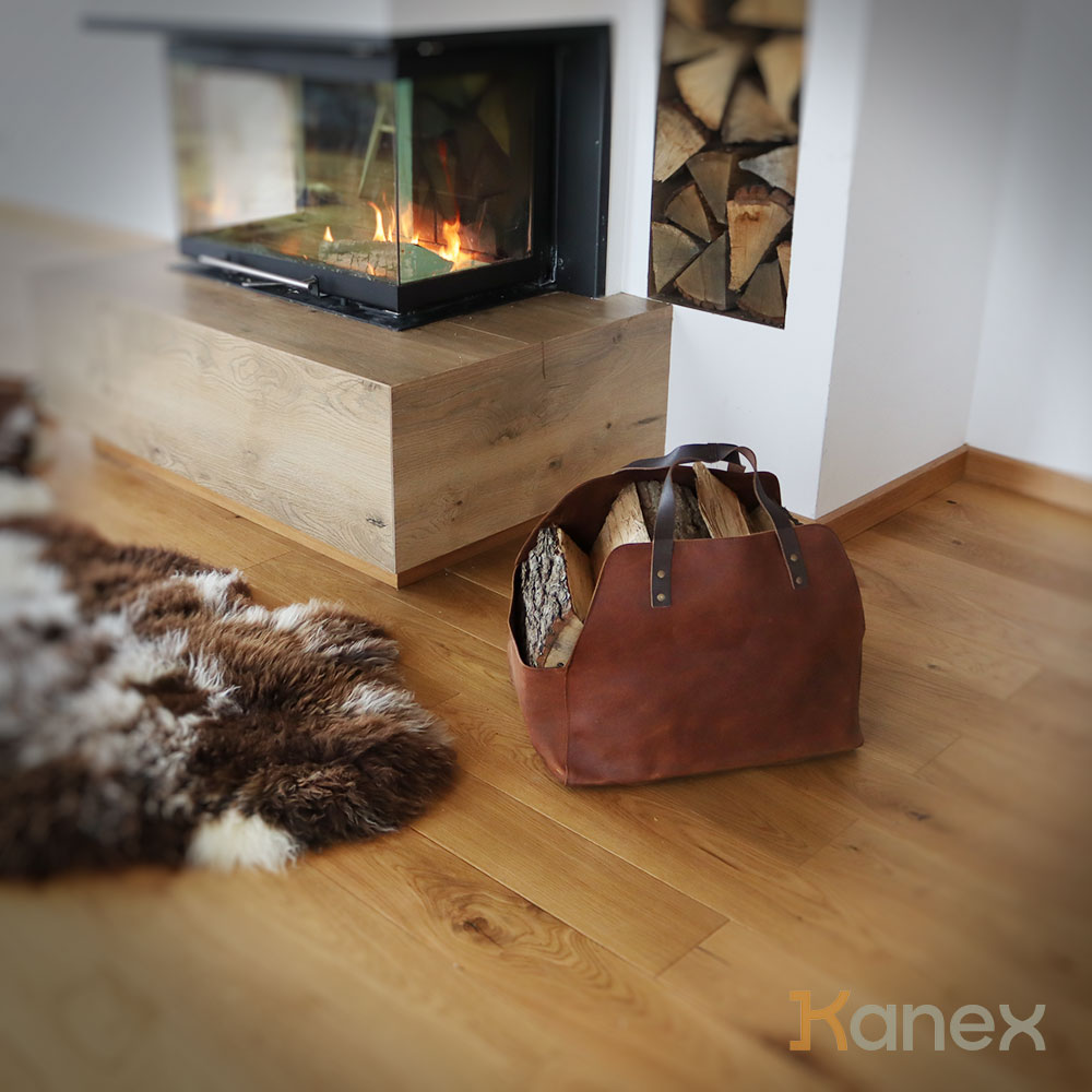 Kaminholztasche aus braunem Rindsleder neben dem Kamin Kaminholztasche aus braunem Rindsleder neben dem Kamin